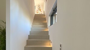Un escalier au design moderne, avec un mur de couleur claire et une petite fenêtre sur le côté droit.