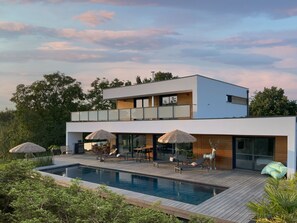 A modern two-story house with a swimming pool, outdoor seating, and a large glass door. - L'escapage Vintage - Villa with swimming pool 15 minutes from Strasbourg city center (Eschau)
