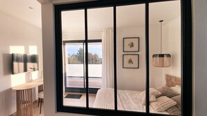 Une chambre moderne dotée d’une grande porte-fenêtre coulissante donnant sur un balcon.