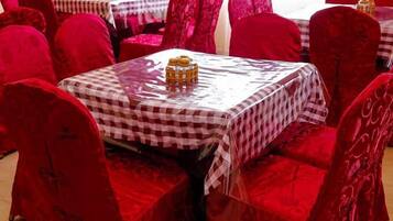 Un ristorante con sedie in velluto rosso e tavoli ricoperti da tovaglie a quadretti.