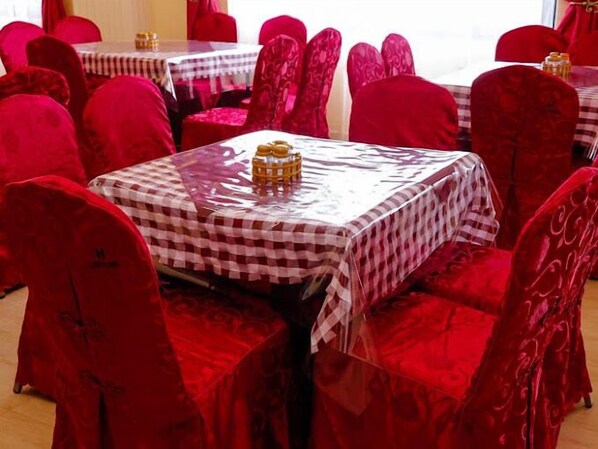 A restaurant with red velvet chairs and tables covered with checkered tablecloths. - Hotel Lintons Busia (Busia)