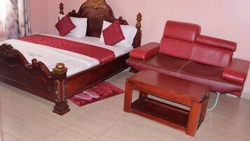 Quarto com cama de madeira, sofá estofado em vermelho e mesa de centro de madeira.