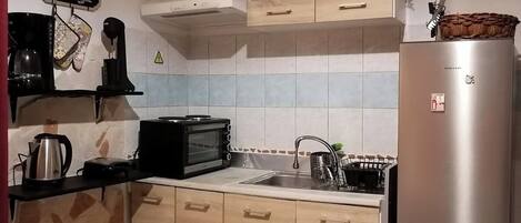 Een oven, een koffiezetapparaat/waterkoker, kookgerei, borden en bestek