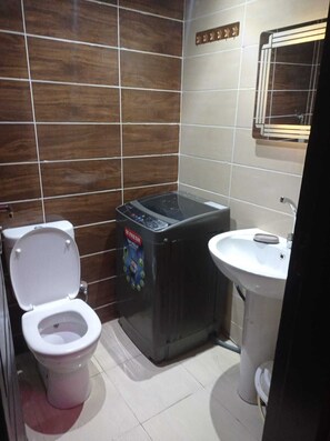 A bathroom with a toilet, a washing machine, and a sink.