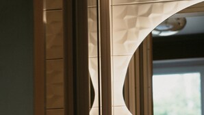 A bathroom with a geometric patterned wall, a wooden door, and a mirror. - HOTEL BLEU SOLEIL (Capbreton)
