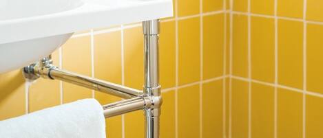 A bathroom with a white sink, chrome fixtures, and yellow tiled walls.