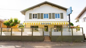 A two-story building with a yellow and white striped awning, a sign reading "BLEU SOLEIL", and a gated entrance. - HOTEL BLEU SOLEIL (Capbreton)