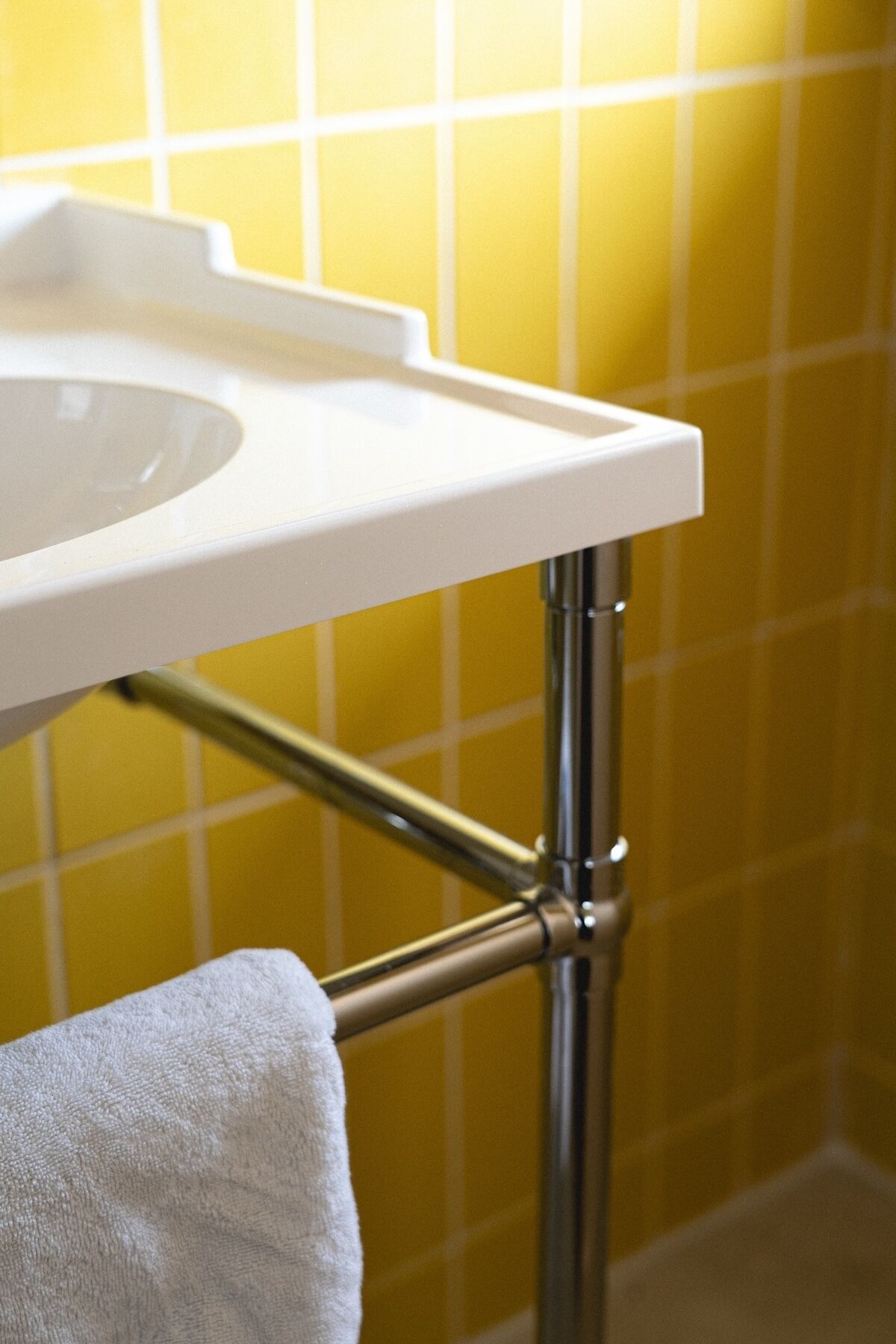 Un lavabo de salle de bain avec un plan de toilette blanc et des tuyaux chromés.