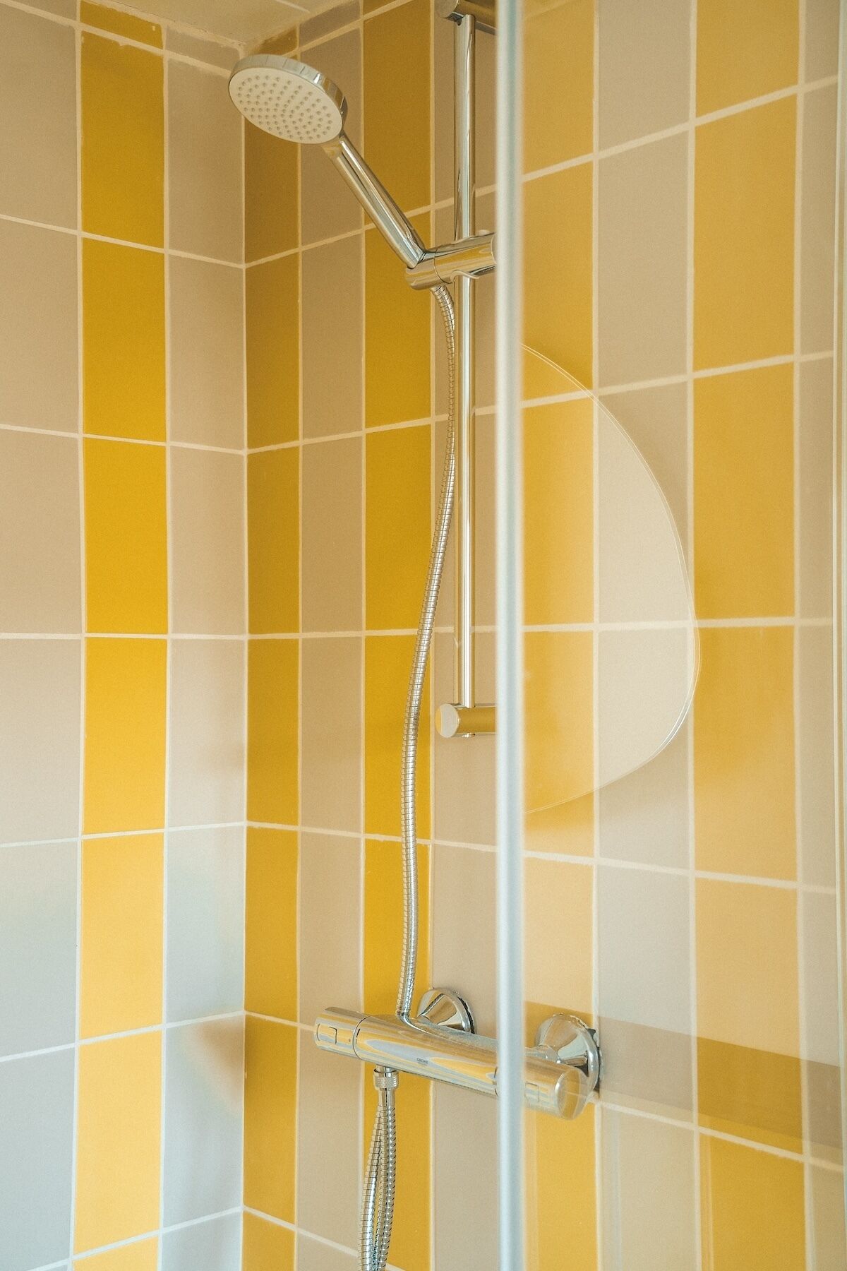 Une douche équipée d’un pommeau de douche à main et d’un panneau de commande fixé au mur.