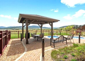 Un patio cubierto con una mesa, sillas, un banco y una pequeña piscina.