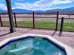 Un jacuzzi con vistas a montañas y un área cercada.