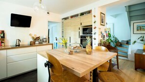 A modern kitchen with wooden cabinets, a dining table, and a TV mounted on the wall. - Quiet family home with terrace - near Ondres beach (Ondres)
