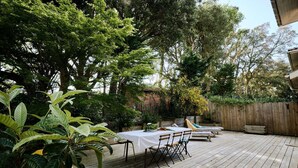 An outdoor patio with a wooden deck, a table set for dining, and various plants. - Quiet family home with terrace - near Ondres beach (Ondres)