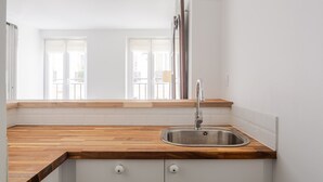 A kitchen with a wooden countertop, a stainless steel sink, and a window with a view of buildings. - Blueground | Gros-Caillou, view, nr Eiffel Tower (Paris)