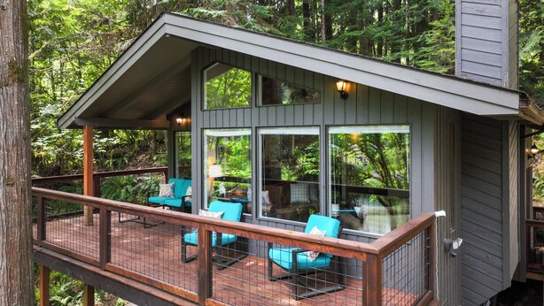 Eine Holzterrasse mit Sitzgelegenheiten im Freien und einer Glaseinfriedung.