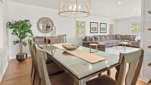 Un salón amplio con un sofá seccional grande, una mesa de comedor de vidrio y una lámpara colgante.