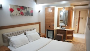 A hotel room with a bed, a small TV, a mirror, a wooden cabinet, and a door. - Hotel İzgi Turhan (Batman)