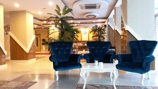 A lobby with two blue armchairs, a white table, and a staircase. - Hotel İzgi Turhan (Batman)