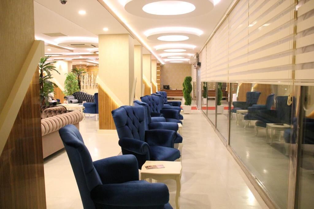Un moderno vestíbulo de hotel con una fila de sillones azules, un mostrador de recepción y una escalera.