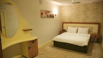 Quarto com cama, mesa de cabeceira e espelho.