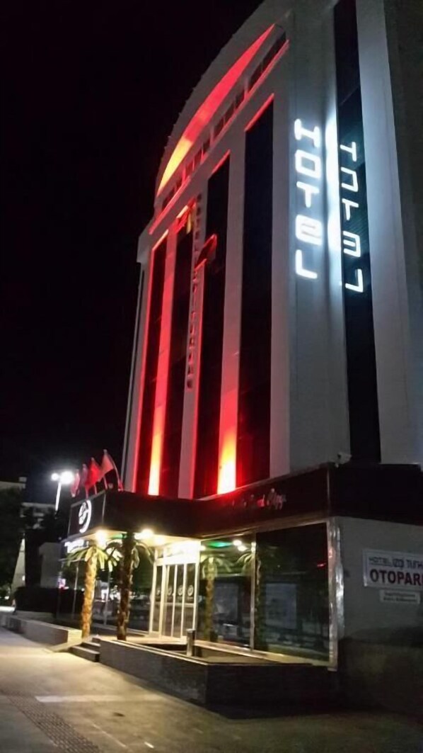 A hotel with a modern facade, large vertical windows, and illuminated signage. - Hotel İzgi Turhan (Batman)