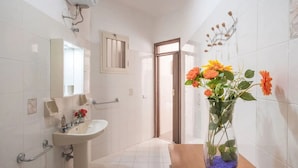 A bathroom with a sink, mirror, and a vase with flowers. - Casa Isidoro, Ac, Seaside (Sant'isidoro)