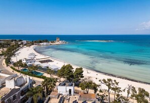 Eine Küstenstadt mit Strand, klarem blauen Wasser und einem Turm in der Ferne.