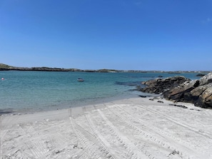 A sandy beach with clear water and rocky outcrops.