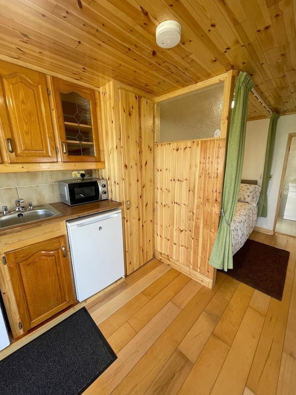A compact kitchen with wooden cabinets, a microwave, a dishwasher, and a small countertop.