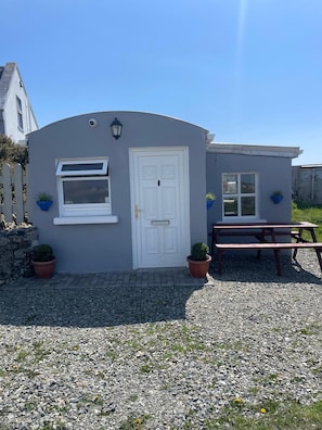 A small building with a white door, a window, and a bench outside.