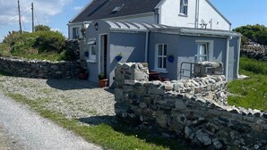 A two-story house with a stone foundation, a grey exterior, and a sloped roof. - Calla Chalet by the Sea Roundstone (Roundstone)