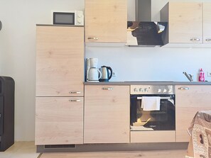 Una cocina compacta equipada con microondas, cafetera, hervidor y horno.