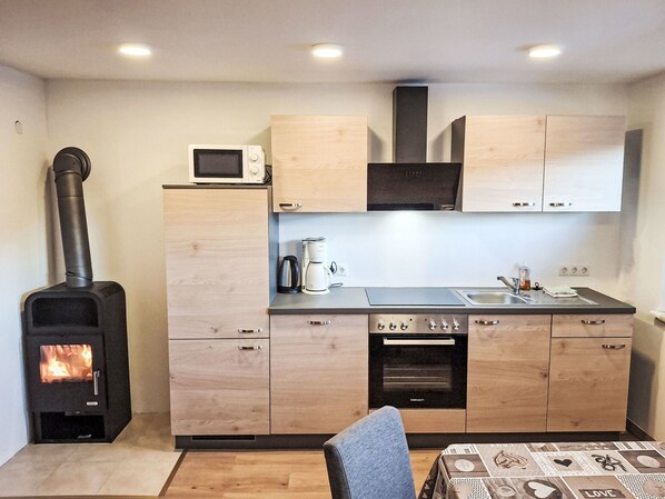 A compact kitchen with a wood-burning stove, a microwave, a coffee maker, and a built-in oven.