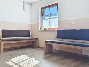 Una habitación con dos bancos de madera, una ventana con cortinas y un enchufe en la pared.