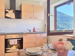 Une cuisine avec des meubles en bois, un four encastré et une fenêtre donnant sur les montagnes.