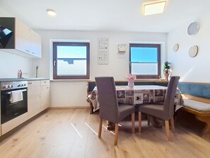 A compact kitchen with a dining area, wooden flooring, and a window with blinds. - Tobias 3 by Interhome (Radstadt)
