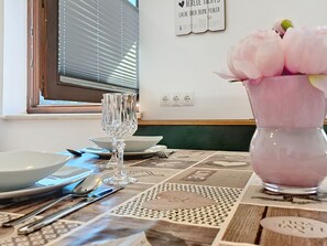 Taula de menjador amb plats, coberts i un ram de flors.