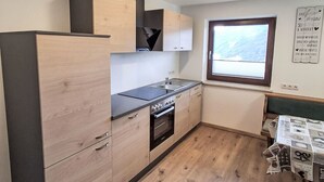 A compact kitchen with wooden cabinets, a built-in oven, and a window with a view.