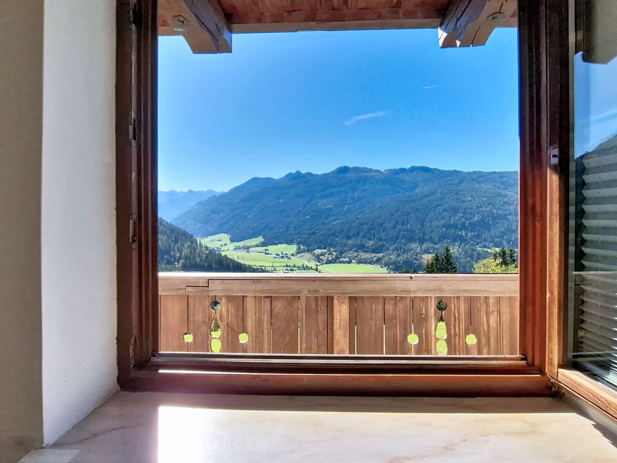 A balcony with a wooden railing and a view of a mountainous landscape.