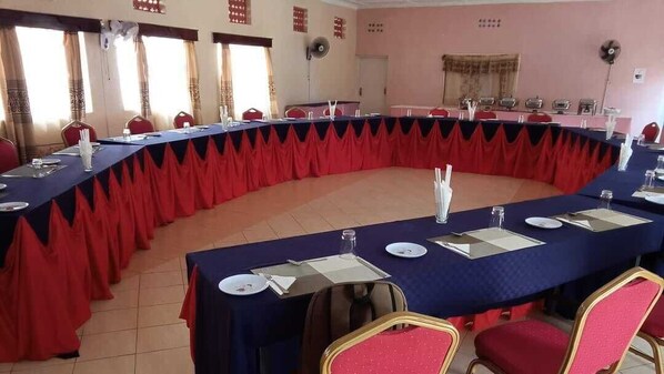 A conference room with a long table, red chairs, and a blue tablecloth. - Farmview Hotel Busia (Busia)