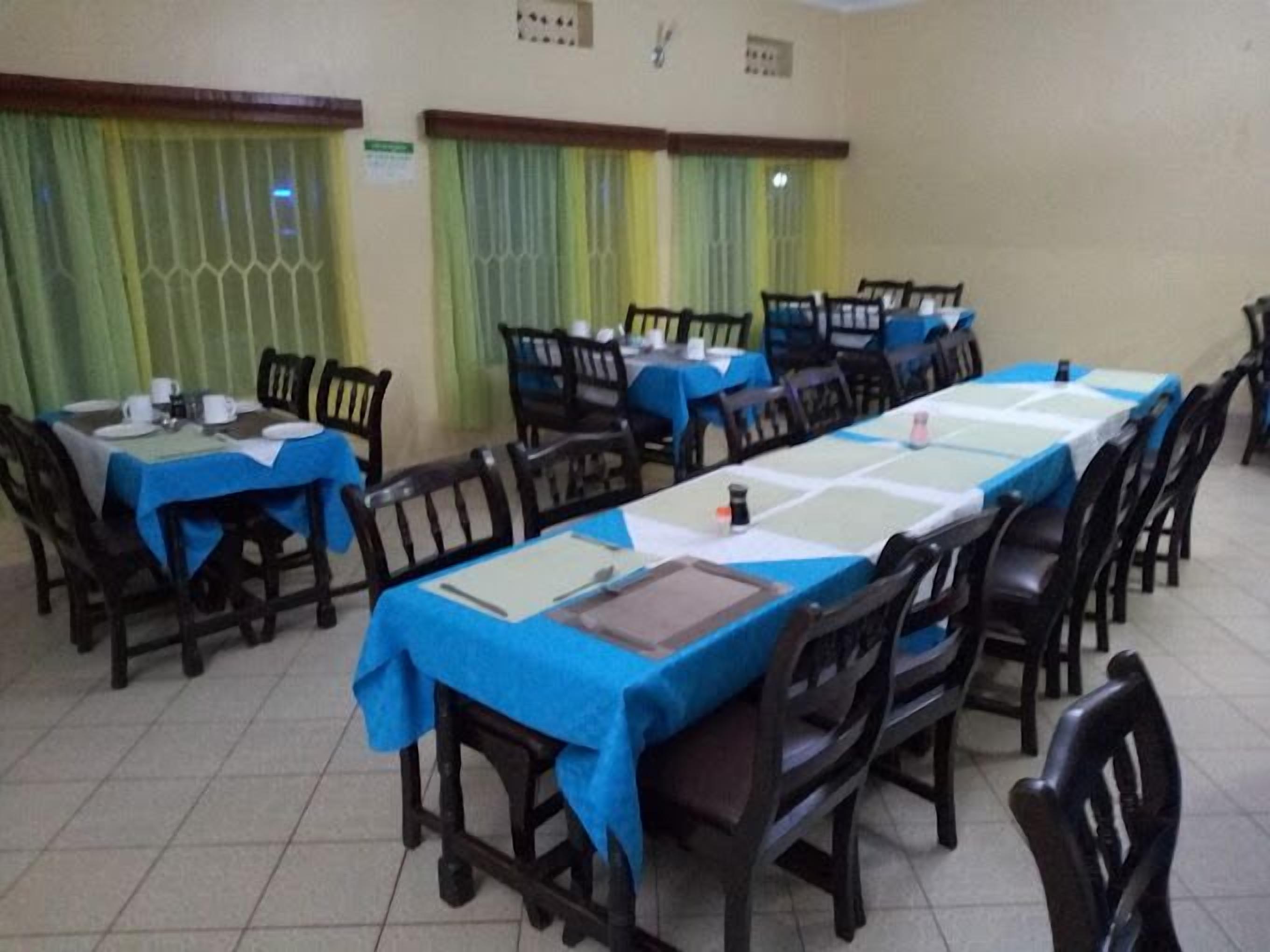 A conference room with multiple tables and chairs, each covered with a blue tablecloth.