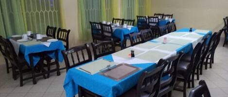 A conference room with multiple tables and chairs, each covered with a blue tablecloth.