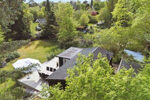 Ein Wohnhaus mit Terrasse, einer kleinen Gartenhütte und einem Teich.