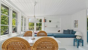 A bright room with a dining table, chairs, a sofa, and a lamp.