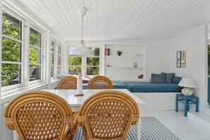 Ein heller Raum mit Esstisch, Stühlen, einer Couch und einer Lampe.