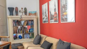 A living room with a red wall, a beige sofa, a bookshelf, and a fireplace.