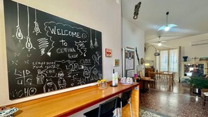 Zona de bar con pared de pizarra, taburetes y cocina al fondo.