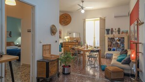 A spacious living area with a dining table, chairs, a sofa, a coffee table, and a bookshelf.