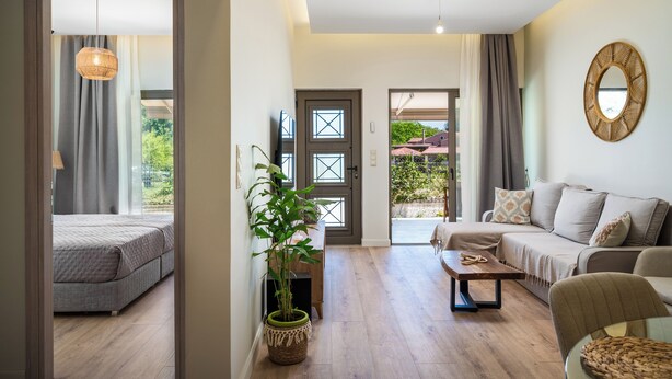 A modern living room with a sofa, a coffee table, and a potted plant. - Phos Elegant Residences by Konnect, 400m to the beach - Two Bedroom Apartment (Corfu)
