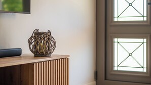 A wooden console table with a woven basket, a flat-screen TV, and a door with glass panels. - Phos Elegant Residences by Konnect, 400m to the beach - Two Bedroom Apartment (Corfu)